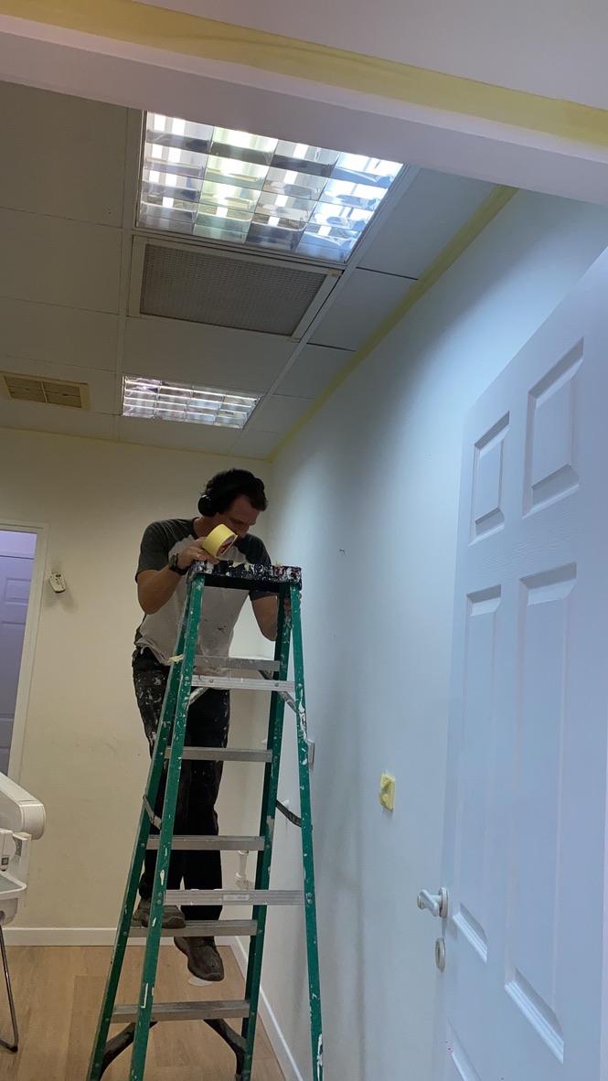 Painter applying masking tape around interior trim